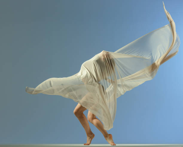 istock Dancer jump on blue background with beige fabric 1409754911