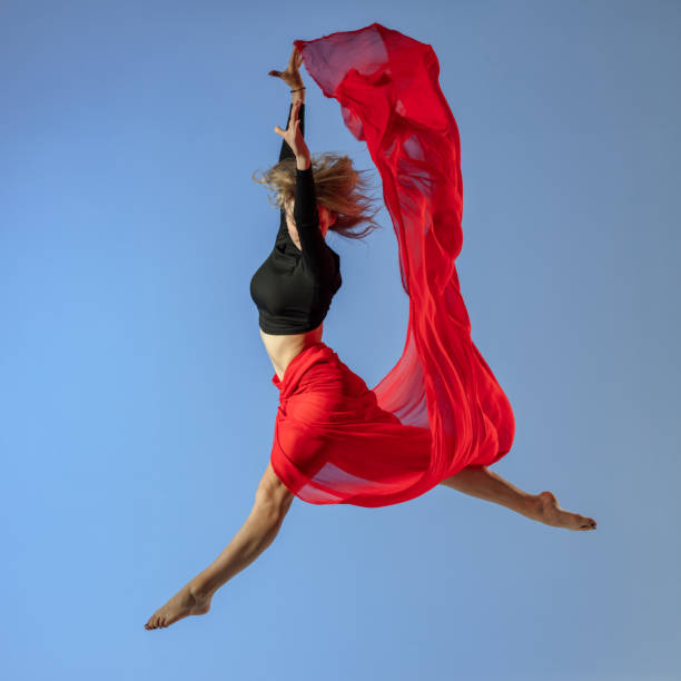 istock Dancer jump on blue background with red fabric 1409755797