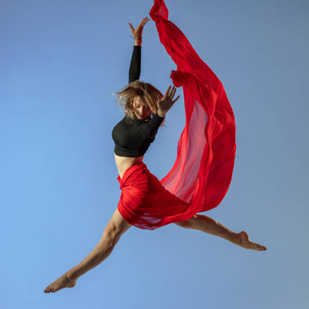 istock Dancer jump on blue background with red fabric 1409755810