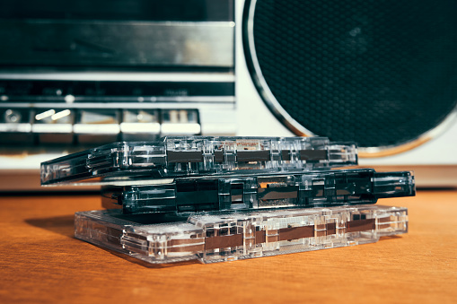 Stacks of 8-track music tapes with a tape deck on a reflective black surface.