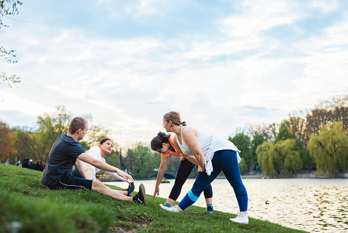 Small group of people stretching after a run by the river, enjoying a healthy lifestyle in the outdoors