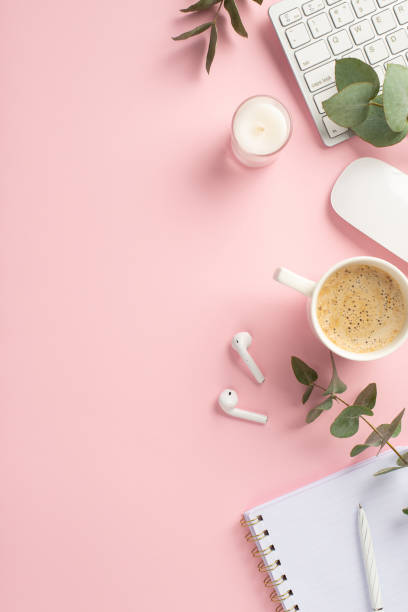 istock Business concept. Top view vertical photo of workspace keyboard candle computer mouse cup of coffee pen open notepad wireless earbuds and eucalyptus on isolated pink background with copyspace 1409757125