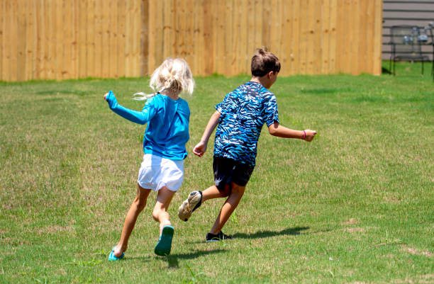 chica persiguiendo a un chico en el patio trasero - color - child running playing tag fotografías e imágenes de stock