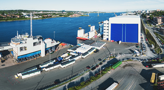 An aerial view of a navy vessel under construction at a large shipyard.