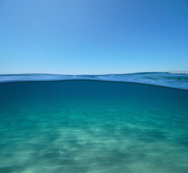 blauer himmel mit sand unter wasser - unterwasseraufnahme stock-fotos und bilder