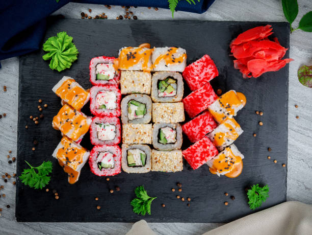 istock Set with fried and baked rolls, sushi on a stone board on a light table 1409761219