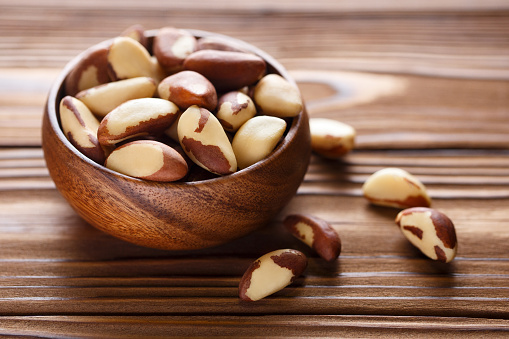 Delicious brazil nuts in wooden bowl on wooden table