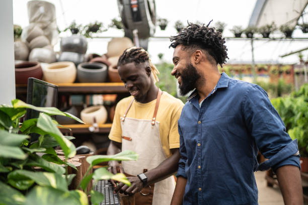 salesman helping customer buying plants at a garden center - florist flower market flower store imagens e fotografias de stock