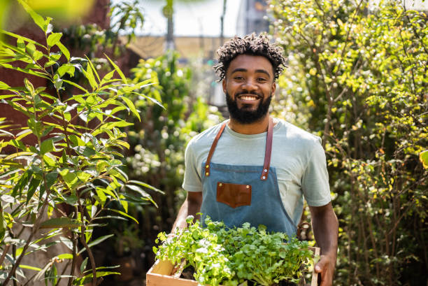 retrato de um jovem vendedor segurando plantas em um centro de jardim - florist flower market flower store - fotografias e filmes do acervo