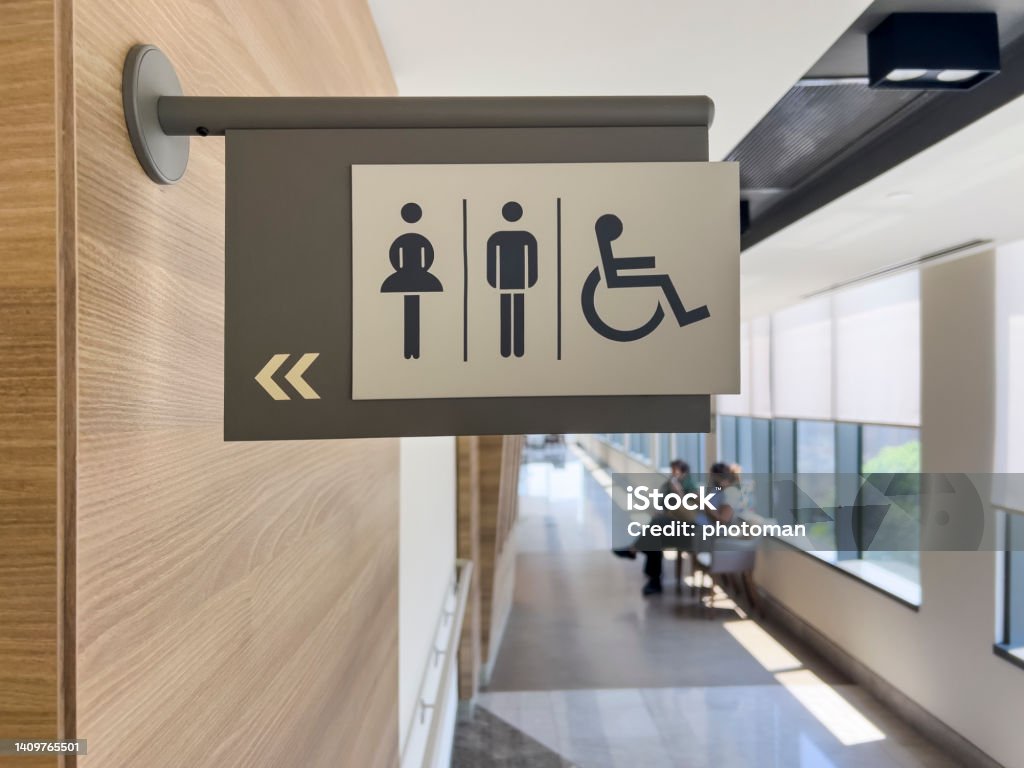 Female, male wheelchair access WC sign International sign concept: Photography of standard known symbols. Illuminated way guiding sign plate on the wall with copy space. Public Restroom Stock Photo