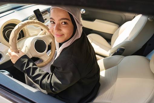 Young arab woman holding the steering wheel of a car with a bright interior