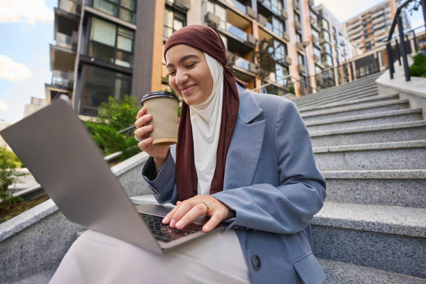 istock Arab woman drinking coffee and typing on laptop 1409766291
