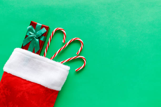 medias navideñas con caja de regalo y bastones de caramelo sobre fondo verde. - medias de navidad fotografías e imágenes de stock