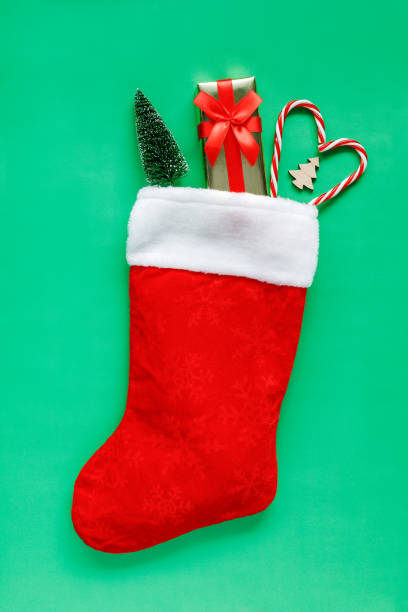 istock Christmas stocking with gift and decorations on green background. 1409768928