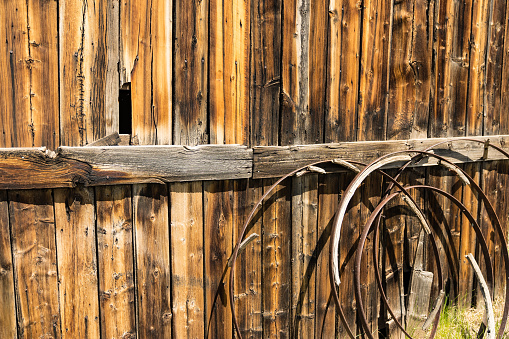 Background of old rusted wagon wheels against a weathered wood barn wall