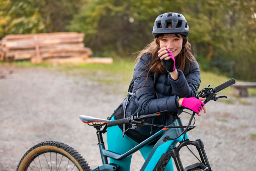 Portrait of a cheerful young woman with her enduro mountain bike (eMTB).