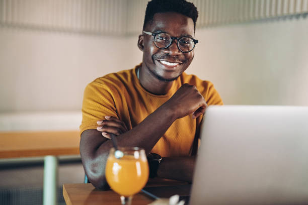 istock Smiling young man with laptop in cafe 1409771636