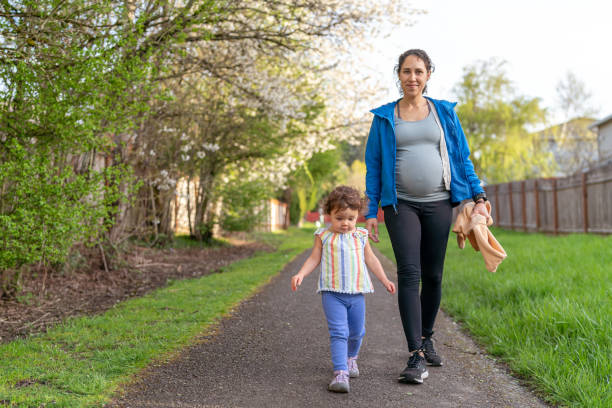 mujer embarazada en un paseo con su hija pequeña - relaxation exercise child mother human pregnancy fotografías e imágenes de stock