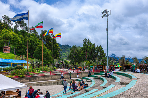 Zipaquira, Colombia - June 30, 2016: Some tourists on the Plaza del Minero near the entrance to the Catedral de Sal, a subterranean church located in an old halite mine, in Zipaquira, in the Cundinamarca Department of the Latin American Country of Colombia. The altitude is 8,690 feet above mean sea level.  People are seen waiting for their turn to enter the mine. Photo shot in the morning sunlight; horizontal format. Copy space.