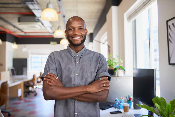 istock An attractive Black man stands with arms crossed in creative office workplace 1409790696