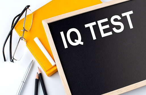 IQ TEST text on blackboard with notepad , pen, pencil