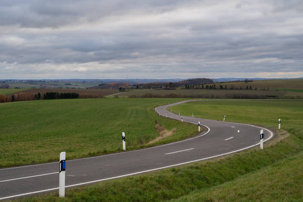 Curvy country road with cloudy sky in the afternoon in autumn