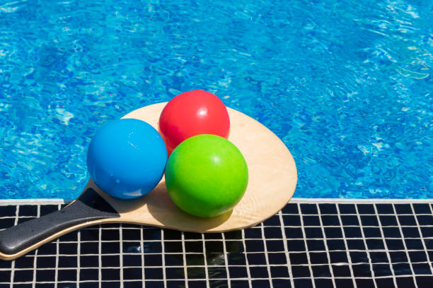 istock Summer play and vacation fun, water games, beach activity and sport concept. Multi-colored balls on beach tennis racket on edge of swimming pool. 1409806803