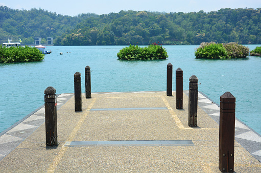 concrete pier on the lake with mountain scenery background on a sunny day with turquoise water, sun moon lake, Taiwan