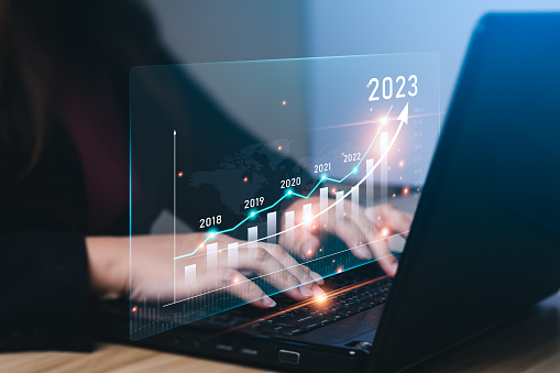 Empresario que planifica el crecimiento del negocio en 2023 en el escritorio con gráfico de holograma virtual. empresario calcula datos financieros para inversiones a largo plazo y objetivos de éxito en el año 2023 photo