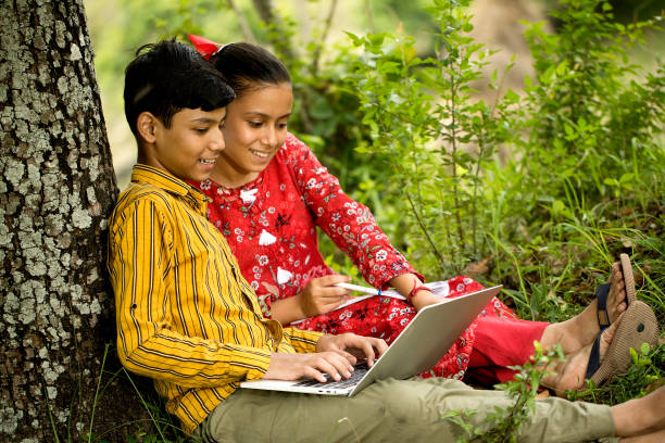 istock Rural boy and girl using laptop outdoors in village 1409815584