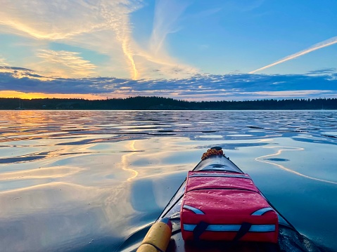 Evening paddle in a kayak with beautiful orange and blue sky sunset colours and cloudsuu