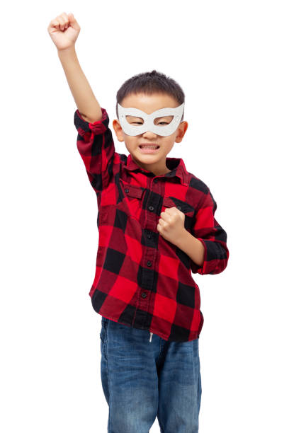 Kid posing superhero with eye mask, wearing red shirt isolated on white background