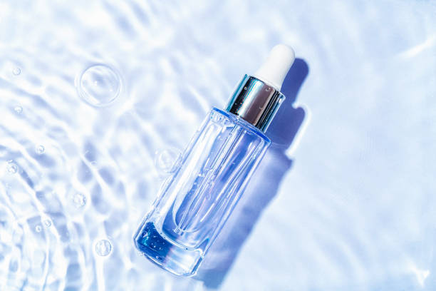 Glass serum bottle with collagen on blue water background with water bubbles. Advertising of medical product for anti-aging care. Cosmetic spa medical skincare. Top view Glass serum bottle with collagen on blue water background with water bubbles. Advertising of medical product for anti-aging care. Cosmetic spa medical skincare. Top view. glass medicine blue bottle stock pictures, royalty-free photos & images