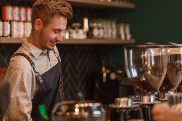 istock Charming male barista standing behind bar counter, making drinks 1409823365