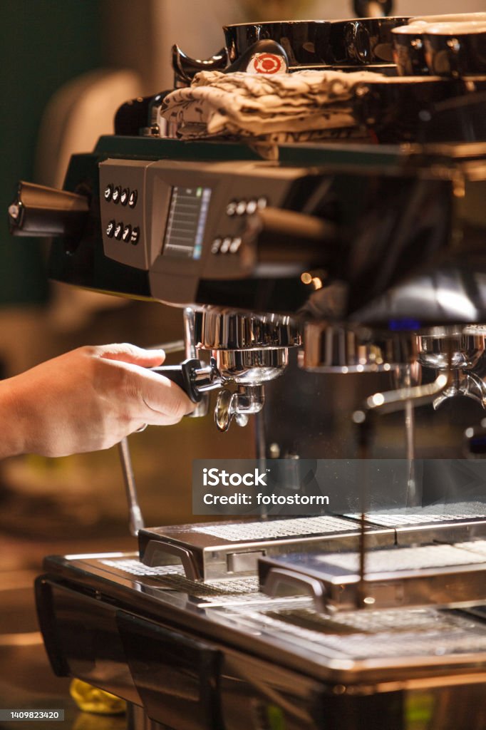 Barista using the espresso maker while preparing customer's order at the coffee shop Close up shot of unrecognizable barista using the espresso maker while preparing customer's order at the coffee shop. 60-64 Years Stock Photo