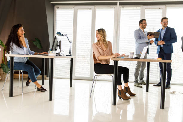 istock Two businesswomen sitting at their desks, making small talk while working 1409823939