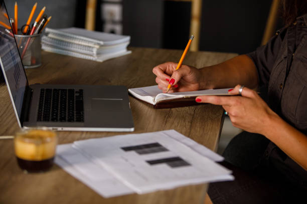 istock Businesswoman writing notes in a notepad while working on a project at her desk 1409824579