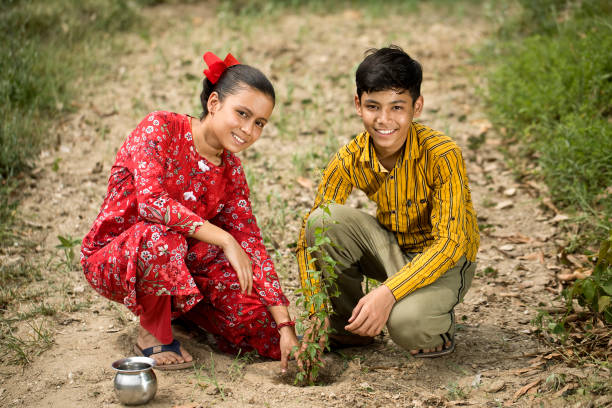 istock Siblings planting a plant on rural field 1409824688