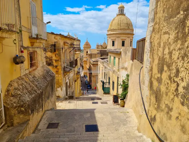 Stairs in Noto with yellow sandstone street and stairs with dome of the cathedral in the background