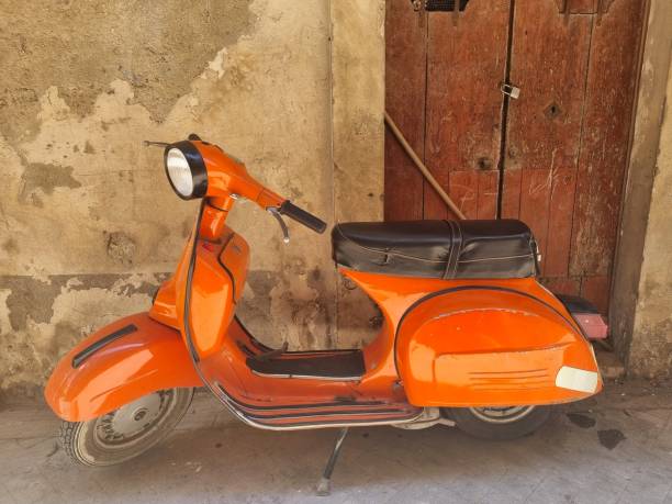 istock Brightly orange colored scooter against stone wall in Sicily 1409828174
