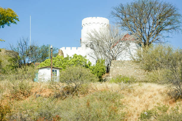 Ancient stone fortress with battlements under a clear blue sky, set in a mountainous landscape.