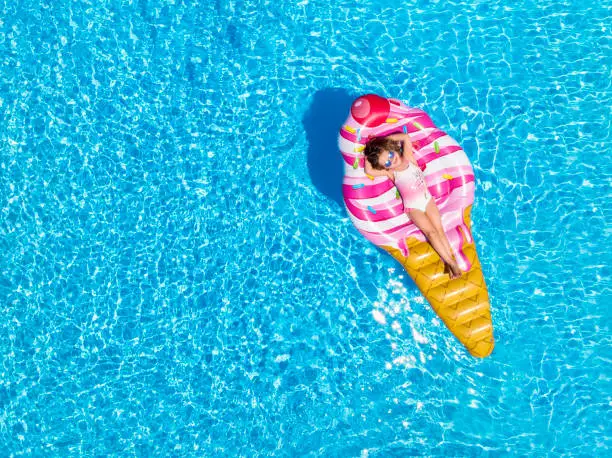 Photo of A blonde girl enjoys a hot summer day on a ice cream shaped float