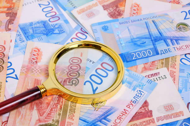 istock Magnifying magnifier against background Russian rubles denominations five and two thousand. 1409829526