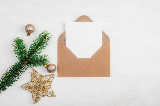 istock Open brown envelope with blank white card and Christmas decorations on white table background. Top view, flat lay, mockup 1409829900