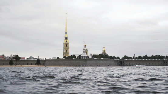 Close up of small waves of neva river and the golden spire of the Peter and Paul fortress. Cloudy sky above the Petropavlovskaya fortress and Neva river.