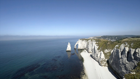 Magnificent white rocky beach and blue sea on horizon. Action. Top view of majestic white cliffs with blue sea at foot and clear sky on horizon in summer.