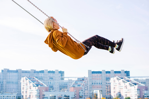 Young woman flying on swing against cityscape