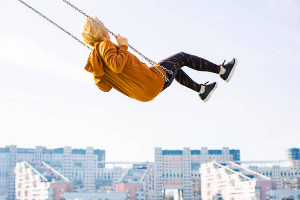 istock Young woman flying on swing against cityscape 1409831480