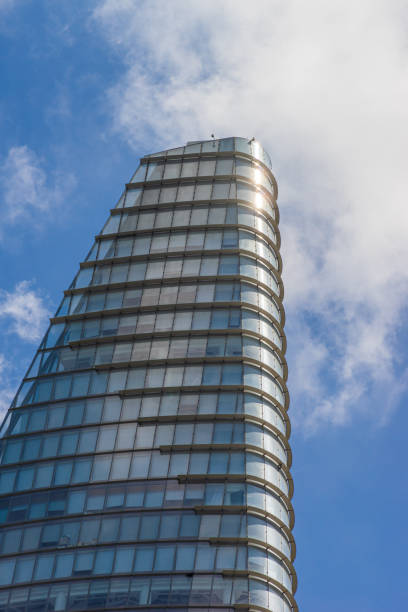 istock Curve glass building and dark steel window system on blue clear sky background, modern office block with sunny beautiful sky. 1409832666