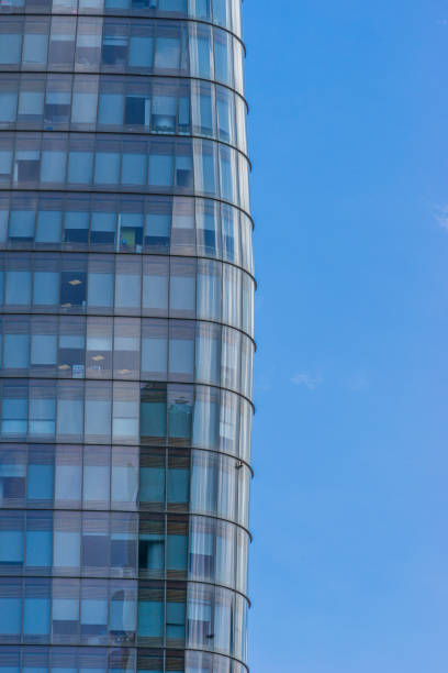 istock Curve glass building and dark steel window system on blue clear sky background, modern office block with sunny beautiful sky. 1409832702